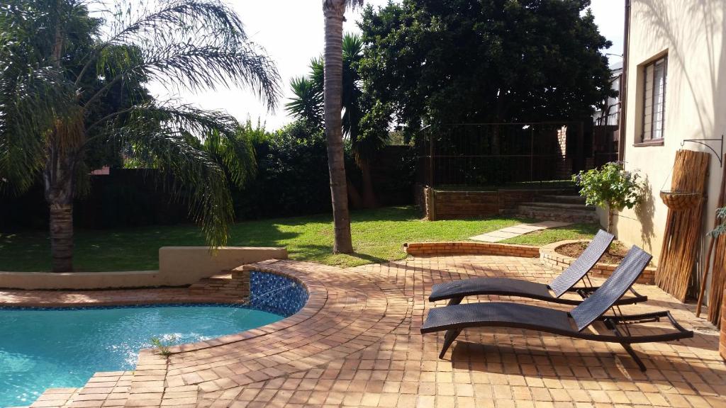 a pool with two lounge chairs next to a house at Private Apartments & Biz Stays Pretoria in Pretoria