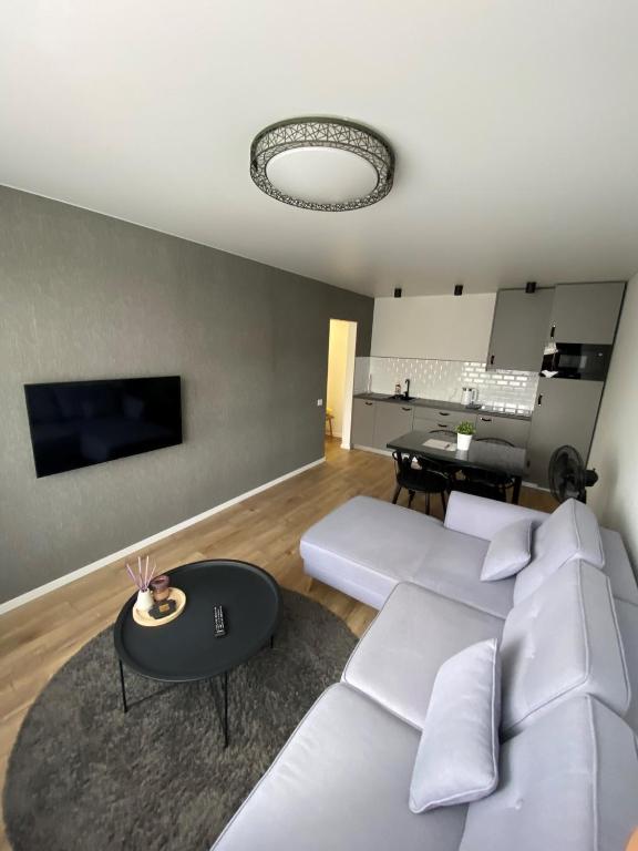 a living room with a white couch and a table at ETG Apartment in Mažeikiai