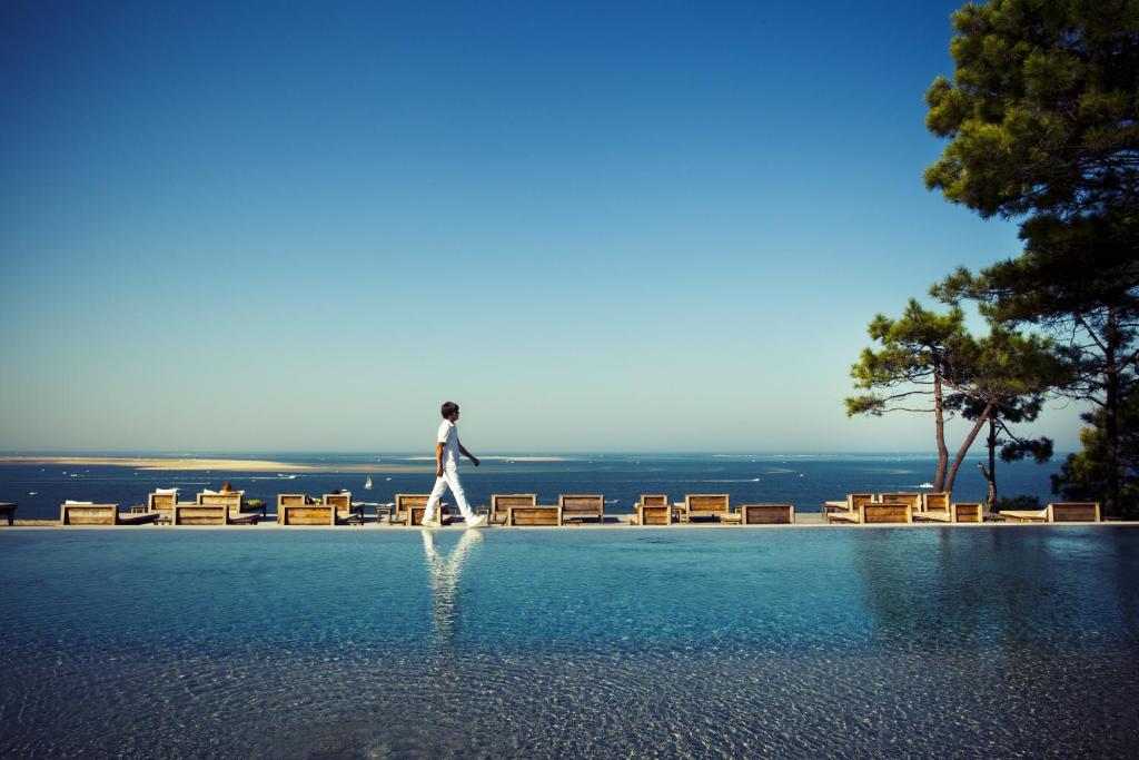 un hombre caminando a través de una piscina de agua en Hotel La Co(o)rniche, en Pyla-sur-Mer