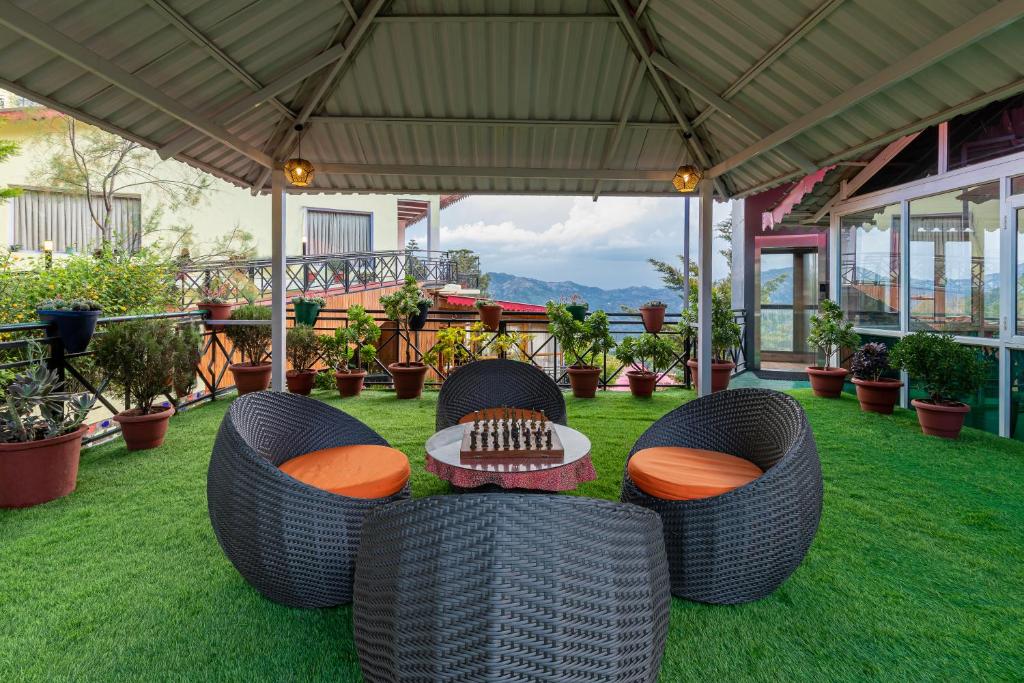 een patio met 2 rieten stoelen en een tafel op het gras bij Maple Resort Chail in Shimla