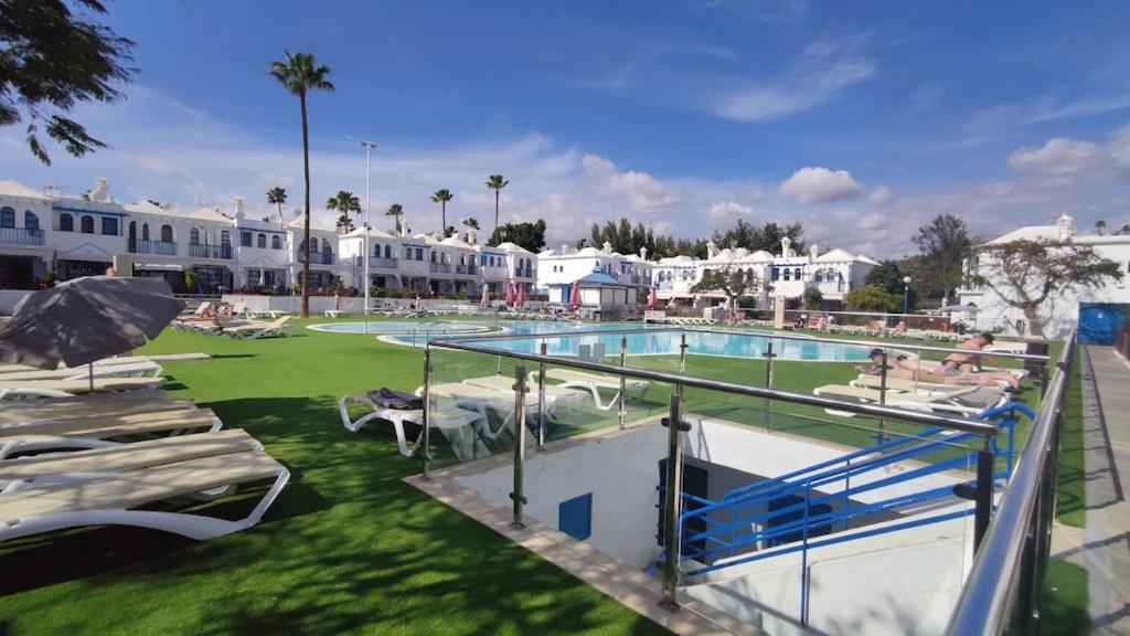 a swimming pool with chaise lounges and a resort at Bungalow in the sun of Maspalomas with large pool in Maspalomas