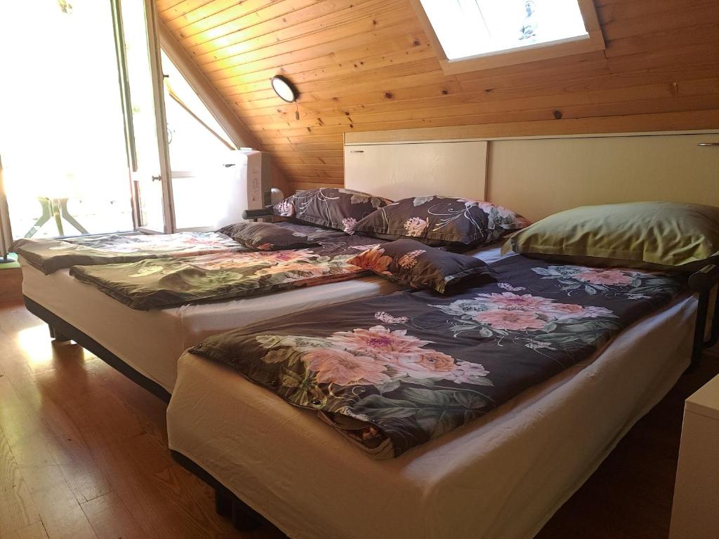 two beds in a room with wooden ceilings and windows at Wooden cabin with a view in Idrija
