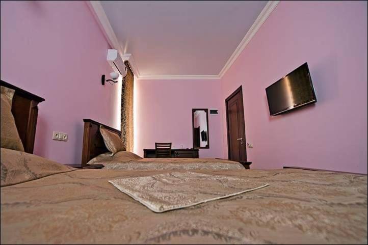 a bedroom with two beds and a pink wall at Eiffel Hotel in Batumi