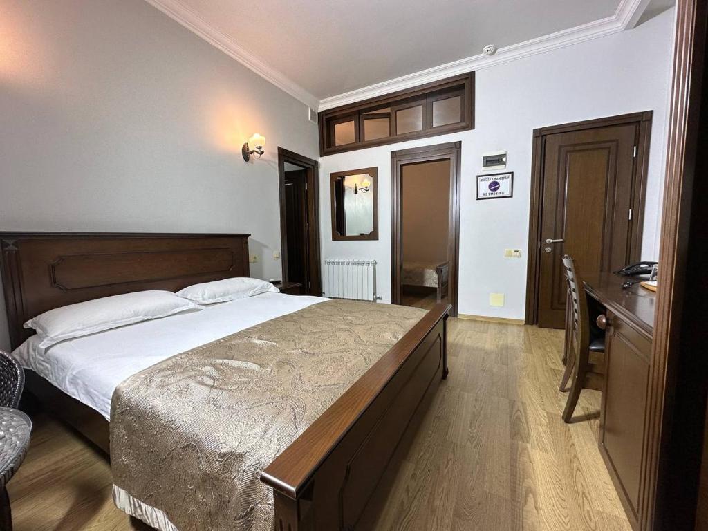 a bedroom with a large bed and a desk at Eiffel Hotel in Batumi