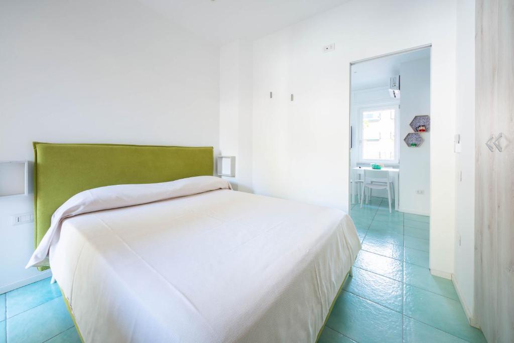 a white bed in a white room with a green headboard at Dependance Panorama in Maiori
