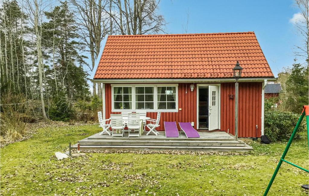 ein rotes winziges Haus mit zwei Stühlen auf einer Veranda in der Unterkunft 2 Bedroom Amazing Home In Grdd in Gräddö