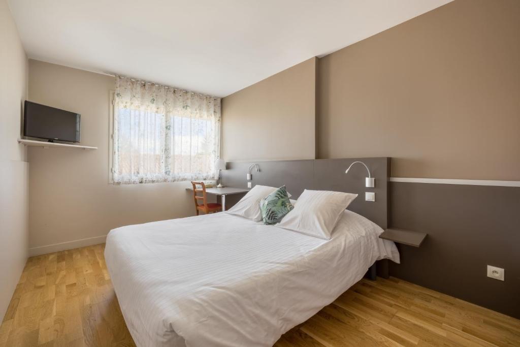 - une chambre avec un grand lit blanc et une table dans l'établissement Hôtel Newport, à Villefranche-sur-Saône