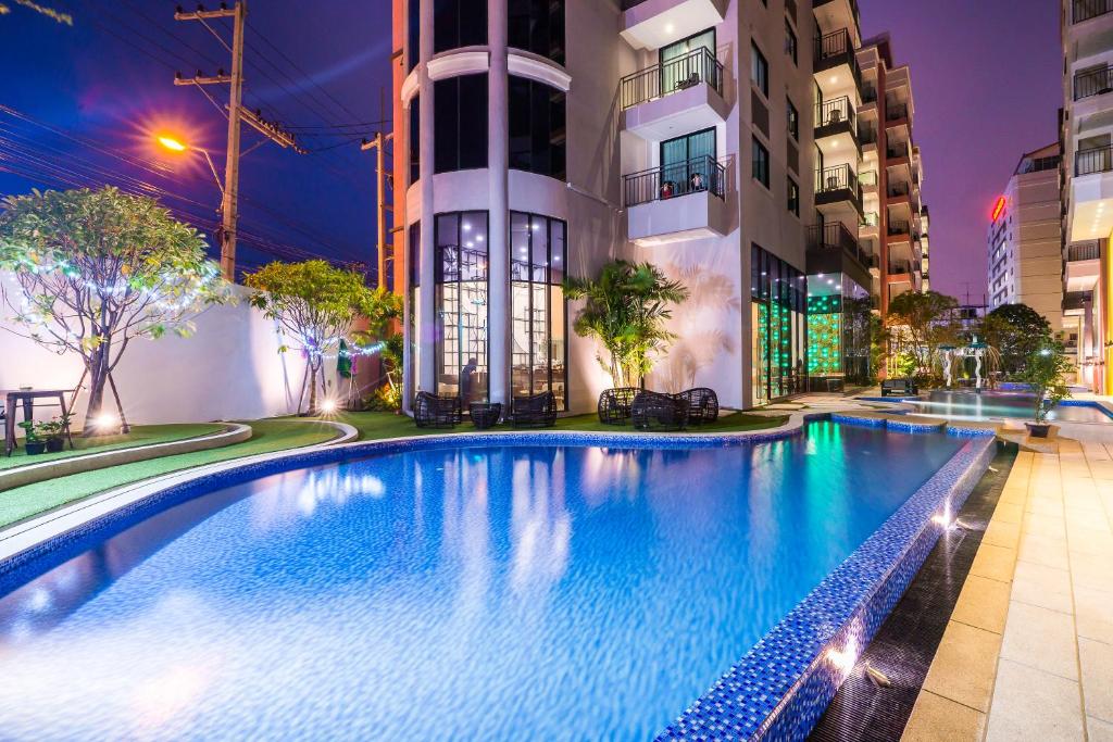 a swimming pool in front of a building at night at Citrus Grande Hotel Pattaya by Compass Hospitality in Pattaya South
