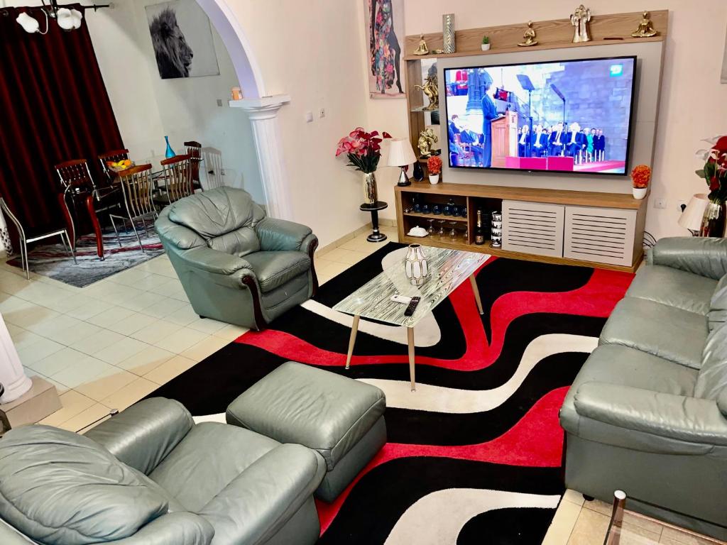 sala de estar con sofás y TV de pantalla plana. en The Palace, en Douala