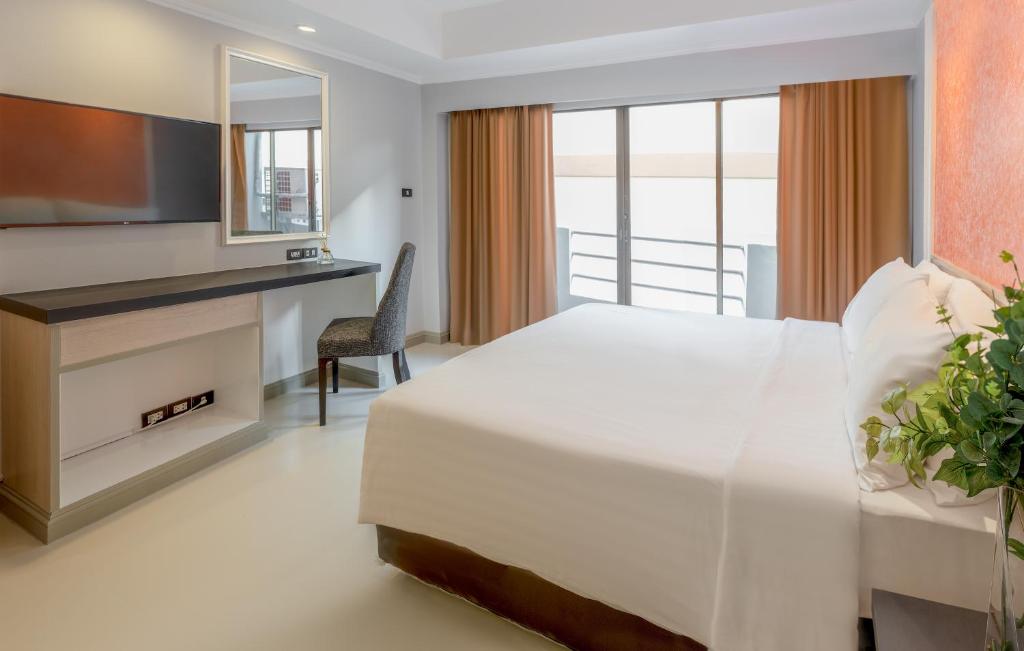 a bedroom with a bed and a desk and a television at FuramaXclusive Sukhumvit in Bangkok