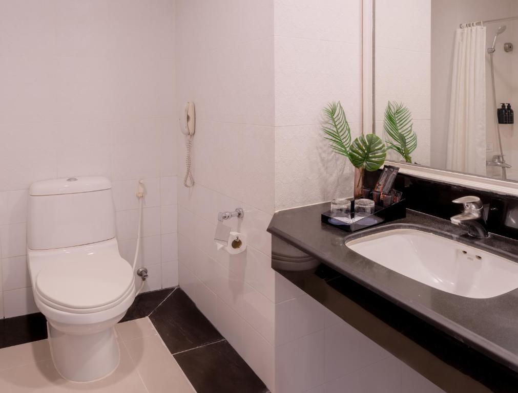 a white bathroom with a toilet and a sink at FuramaXclusive Sukhumvit in Bangkok
