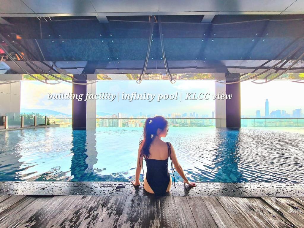 a woman sitting on the edge of a swimming pool at M city service suite KLCC in Kuala Lumpur