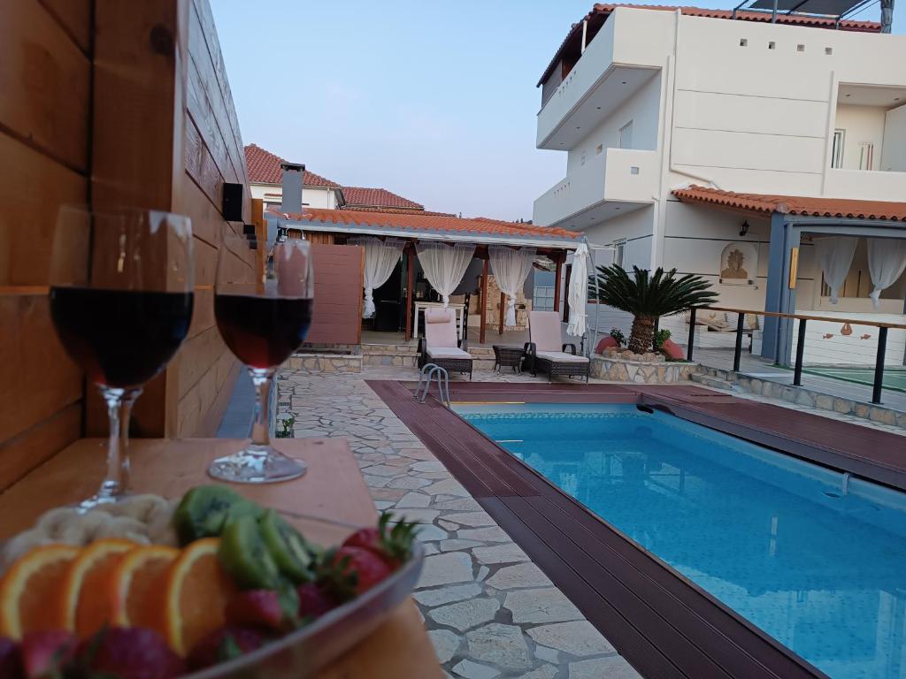 - une table avec des verres à vin et un bol de fruits à côté de la piscine dans l'établissement Local Paradise Xilokastro, à Xylokastro