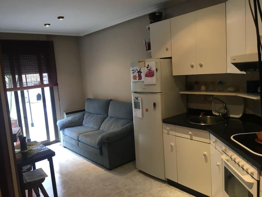 uma cozinha com um frigorífico e um sofá num quarto em Apartamento en el centro de asturias em Langreo