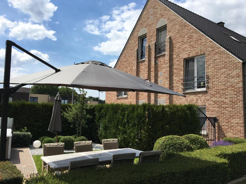 a patio with an umbrella and a table and chairs at Le fond d'Or in Borgloon