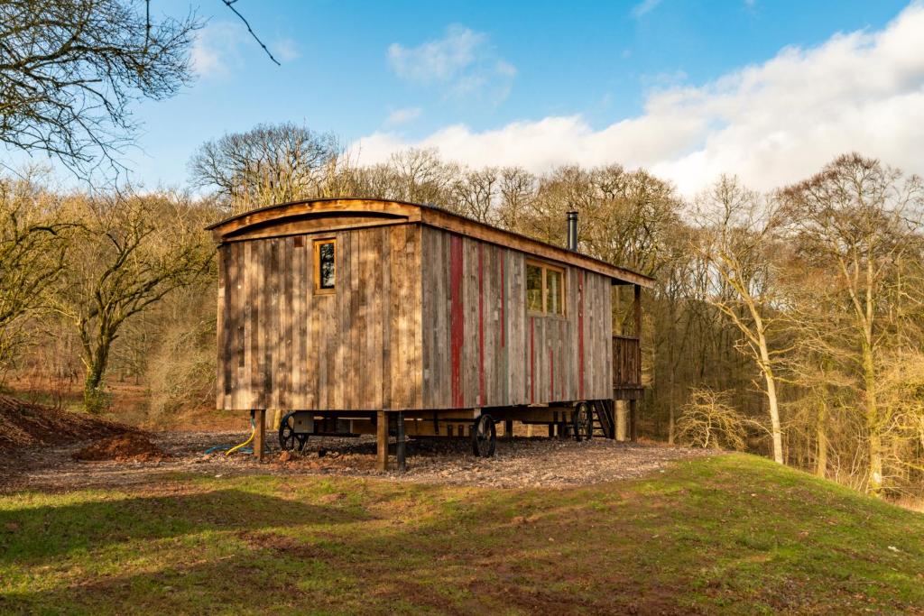 un viejo cobertizo sentado en la parte superior de un campo en Bertha Shepherd's Hut en Lydney