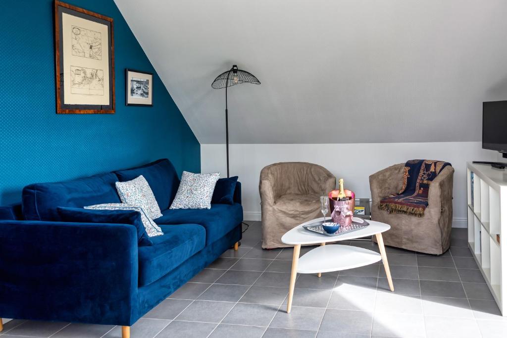 L'Abri du Bon Vent في كانكال: غرفة معيشة مع أريكة زرقاء وكرسيين