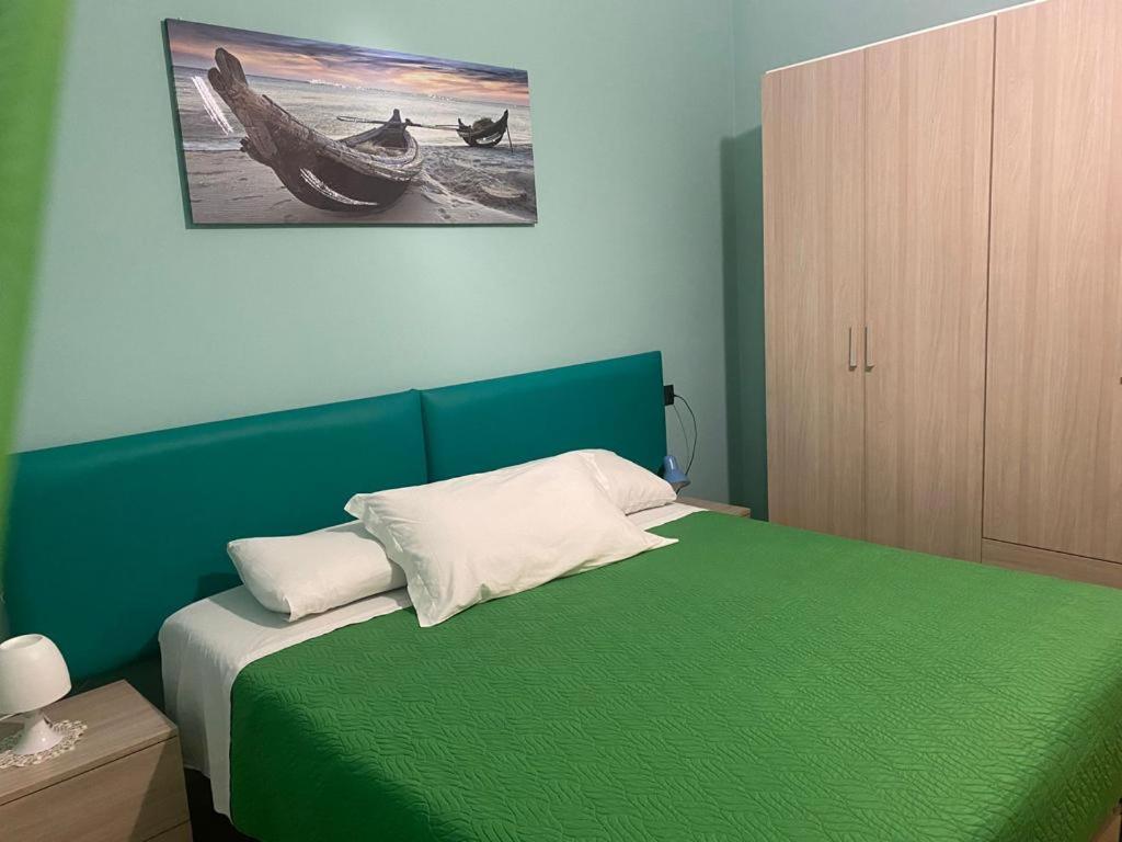 a bedroom with a green bed with a wooden cabinet at The Orange House in Assemini