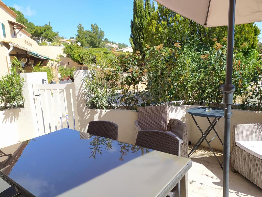 un patio avec une table, des chaises et un parasol dans l'établissement Vacance location mer piscine var sud terrasse, aux Issambres