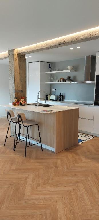 a kitchen with a counter and two chairs in a room at Alojamiento moderno y sofisticado con vistas a la ciudad in Bilbao