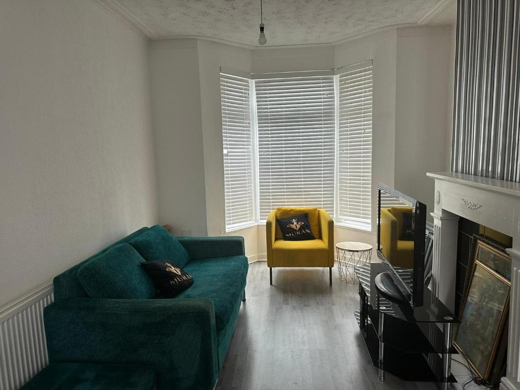 een woonkamer met een groene bank en een gele stoel bij Muram Properties in Kirkby