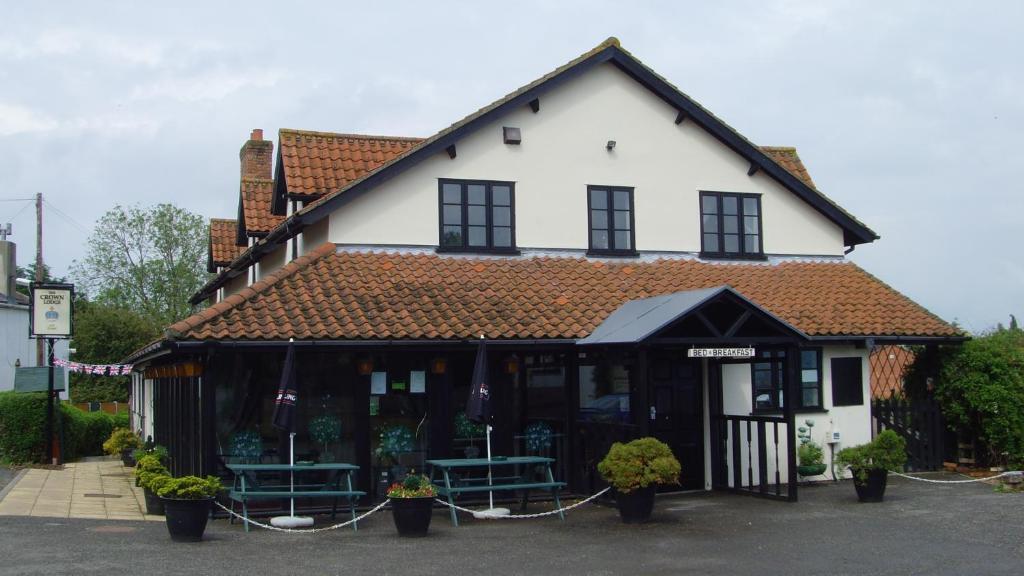 a white and black building with benches in front of it at The Crown Lodge Bed & Breakfast in Dogdyke