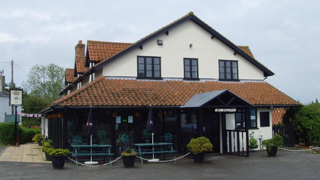 a white and black building with benches in front of it at The Crown Lodge & Restaurant in Dogdyke