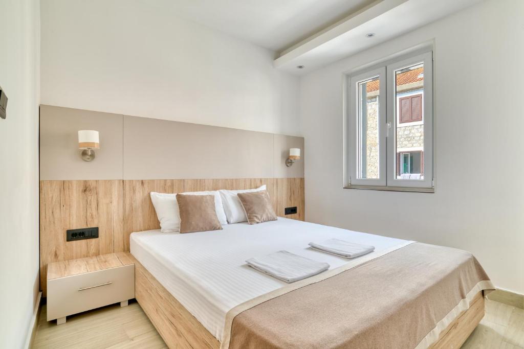 a white bedroom with a large bed with a window at Symphony Apartments Street View in Petrovac na Moru