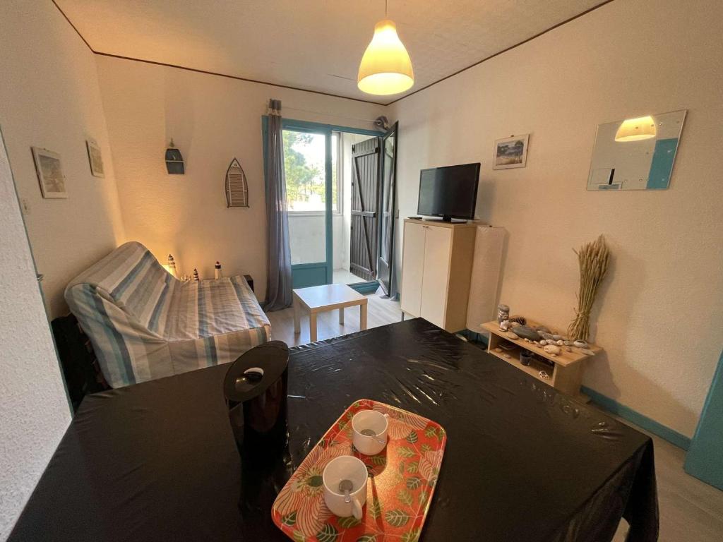 un salon avec une table et un réfrigérateur dans l'établissement Appartement cosy 2 pièces à 200m de la plage, Saint-Hilaire-de-Riez - 4 couchages, parking, TV, WiFi - FR-1-224C-294, à Saint-Hilaire-de-Riez