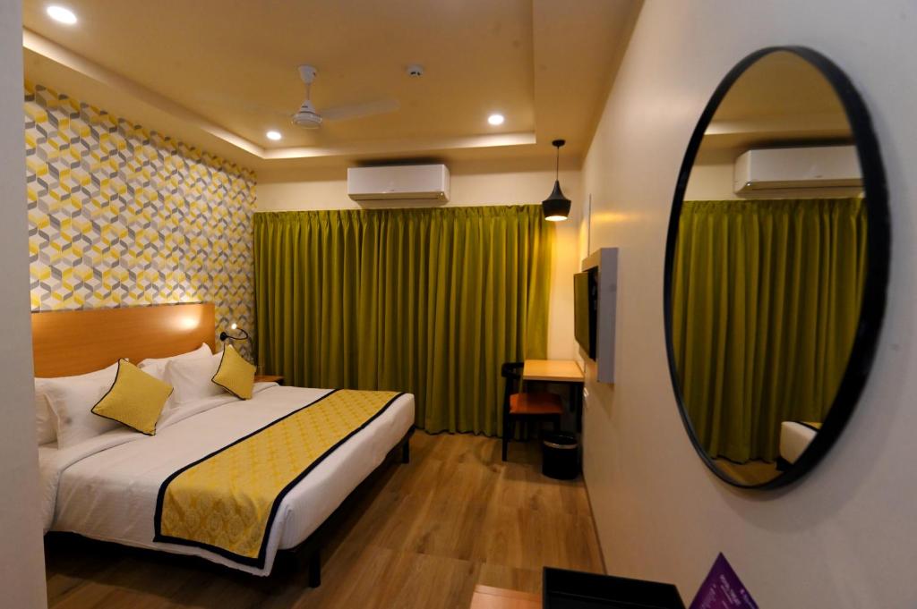 um quarto de hotel com uma cama e um espelho em Regenta Inn Bannerghatta Bangalore em Bangalore