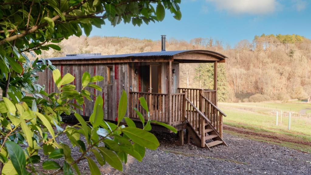 a small wooden cabin with a staircase in a field at Betty Shepherd's Hut in Lydney