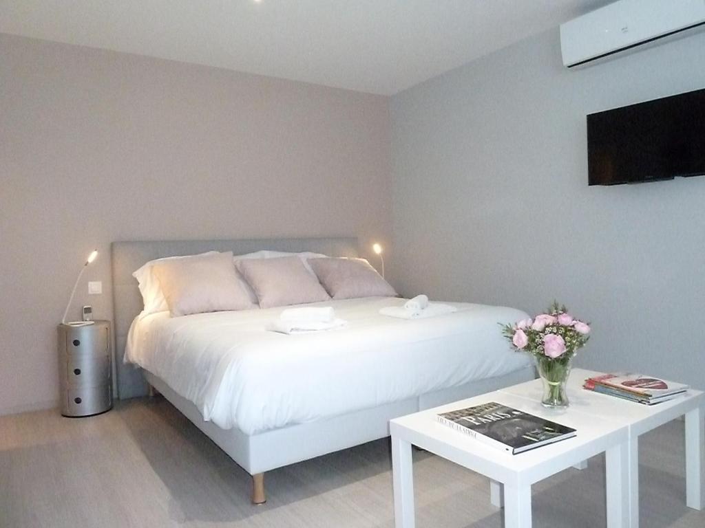 Un dormitorio con una cama blanca y una mesa con flores en Studios Albri, en Nogent-sur-Marne