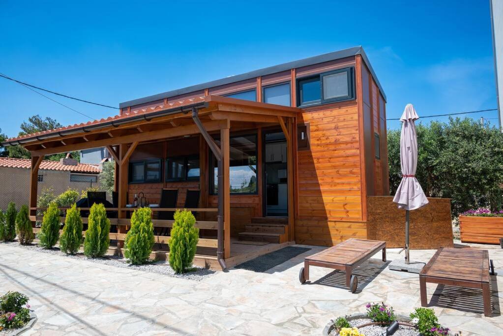 ein Holzhaus mit einer Terrasse und einem Sonnenschirm in der Unterkunft Tiny Villa among the olives in Iraklio