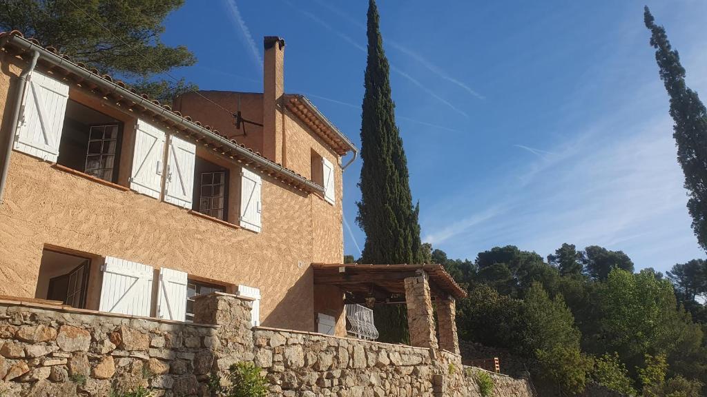 un bâtiment avec un grand arbre à côté d'un mur de pierre dans l'établissement chambre d'hôtes cotignac, à Cotignac