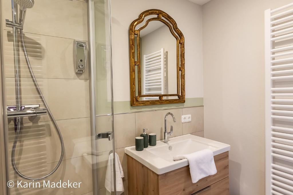 a bathroom with a sink and a shower with a mirror at Design Ferienwohnung mit Bauerngarten in Waldkirchen