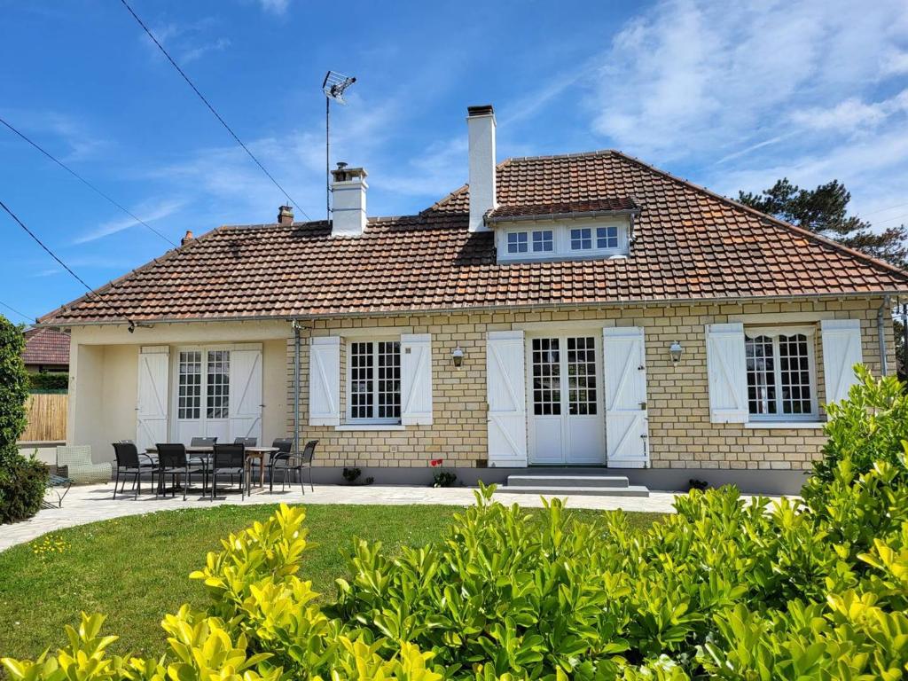 une maison avec une table et des chaises dans une cour dans l'établissement Maison Familiale, Plage à 250m, Calme, Jardin, Terrasse, WIFI - FR-1-465-75, à Merville-Franceville-Plage