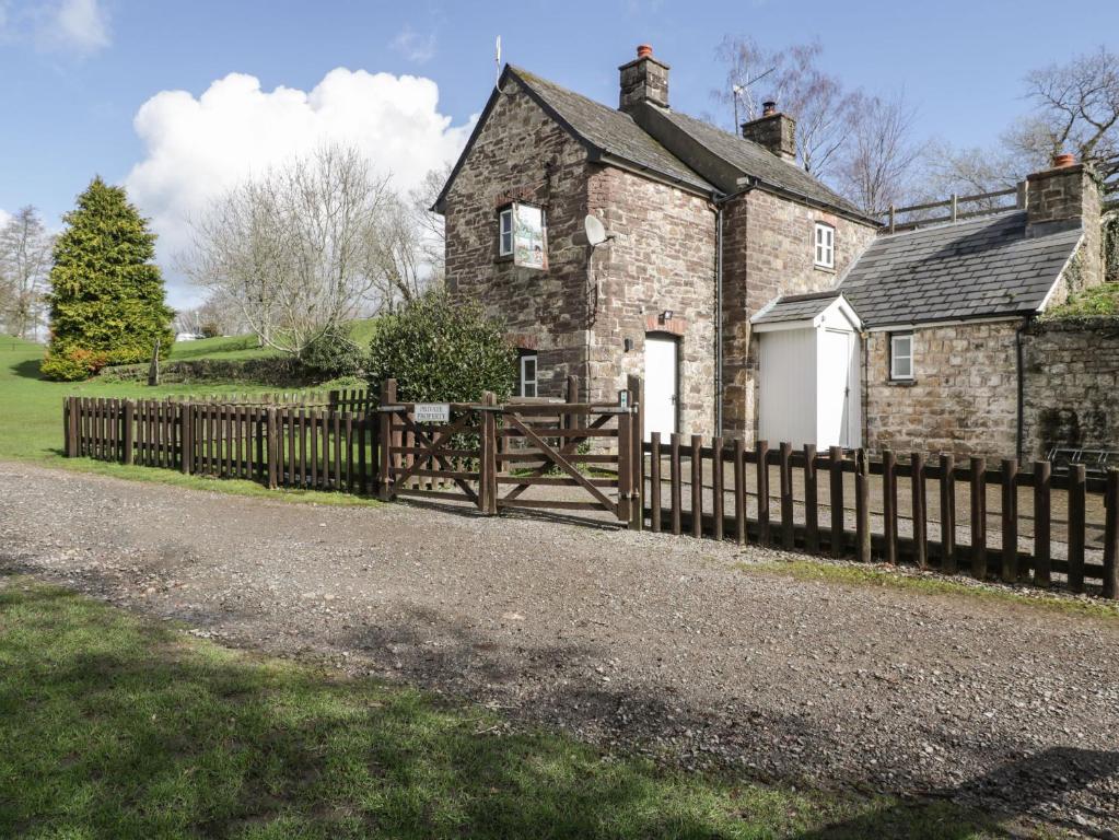 an old stone house with a wooden fence at Aqueduct Cottage in Abergavenny