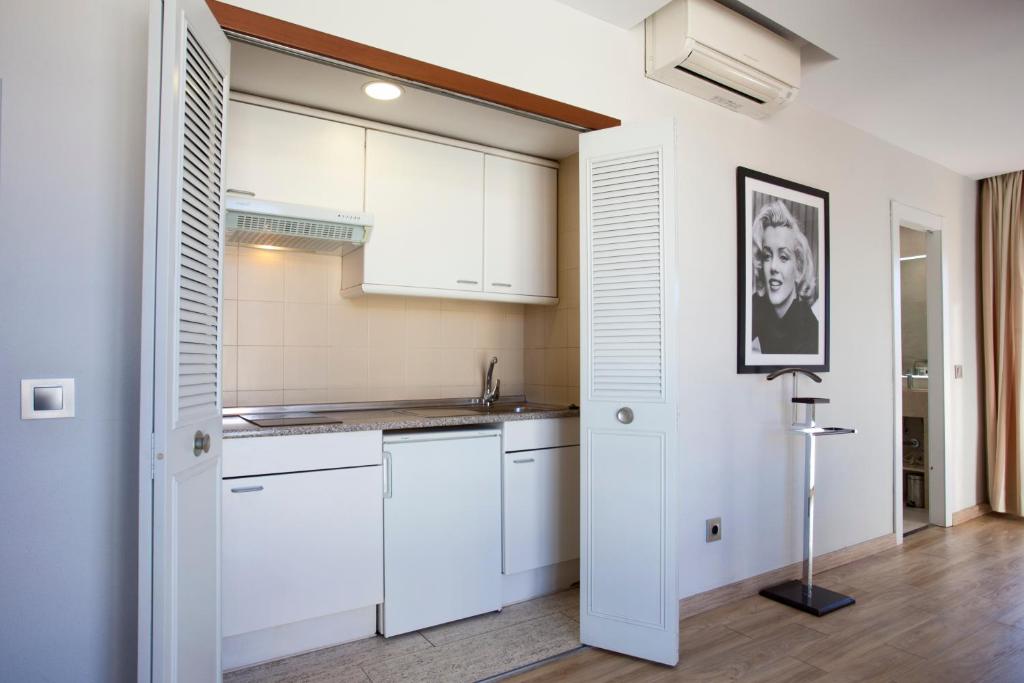 a kitchen with white cabinets and a picture on the wall at Espahotel Plaza Basílica in Madrid