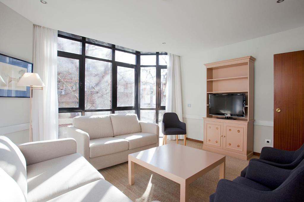 a living room with a couch and a tv at Espahotel Plaza Basílica in Madrid
