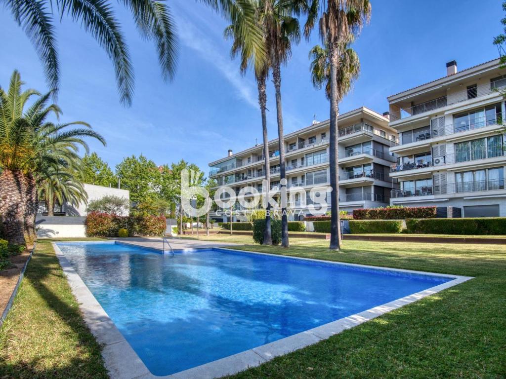 a swimming pool in front of a building with palm trees at Gavines del Port in Platja d'Aro