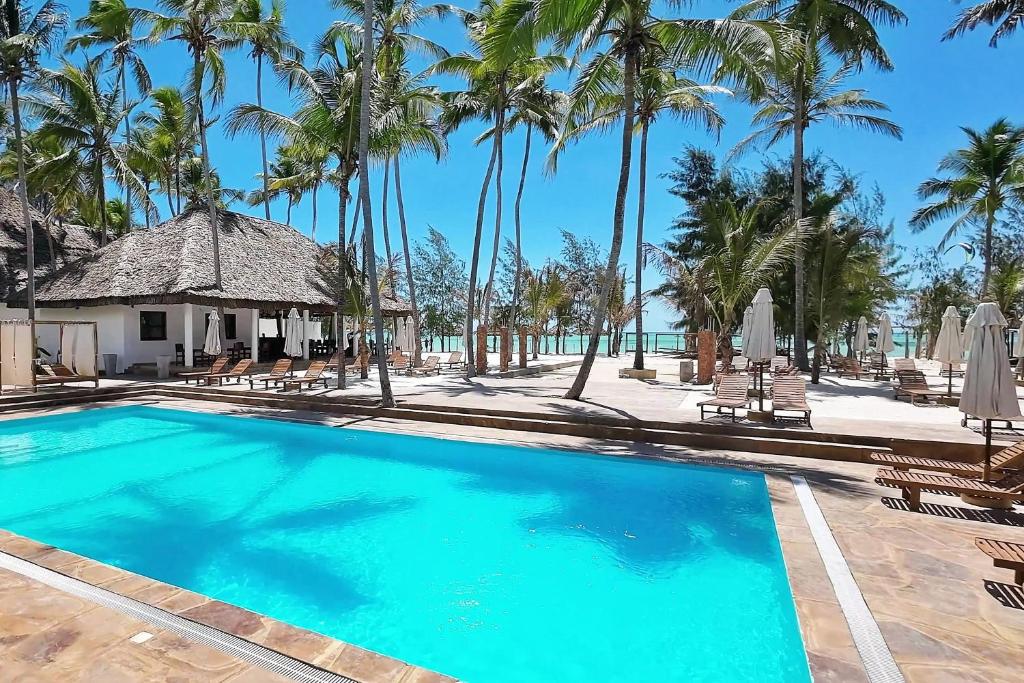 a swimming pool at a resort with palm trees at SBH Monica Zanzibar in Paje