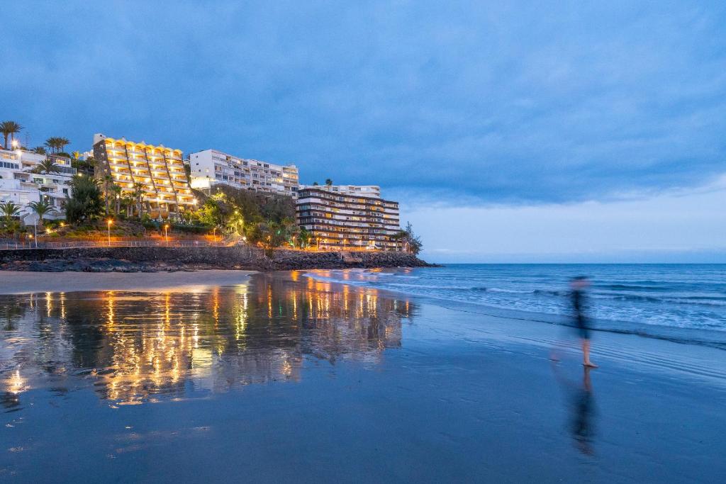 Apartamentos Buganvilla - Adults Only في سان أغوستِن: شخص يمشي على الشاطئ بالقرب من المحيط