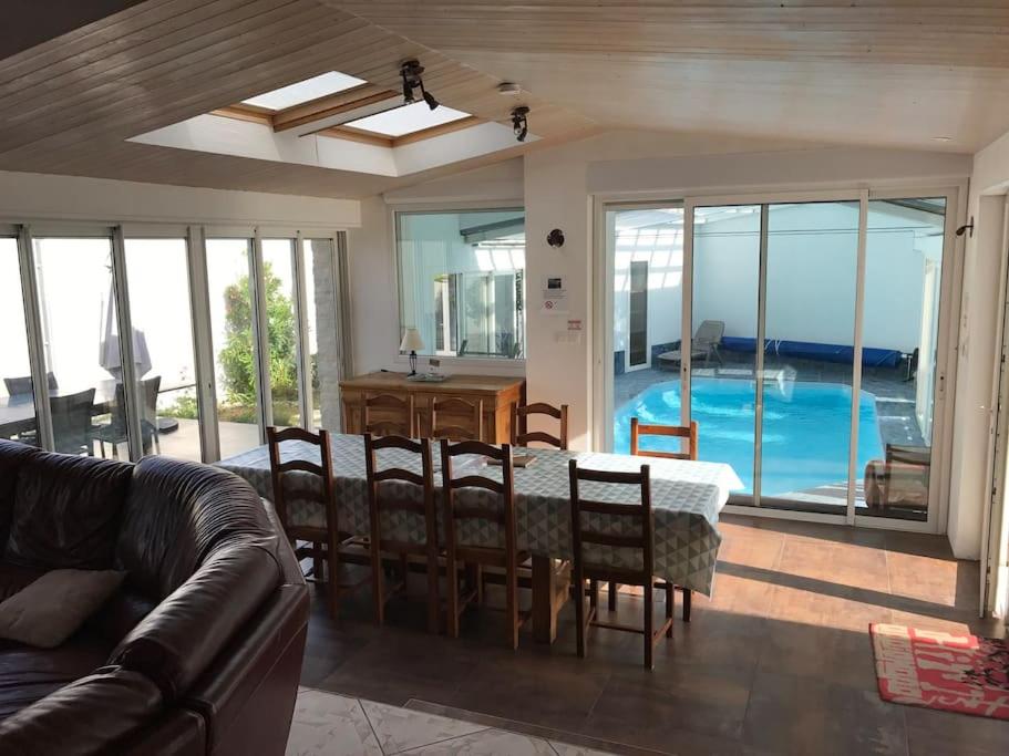 ein Wohnzimmer mit einem Tisch, Stühlen und einem Pool in der Unterkunft Île de Ré -LE CLOS DES AJONCS-Villa de charme avec piscine couverte-8 à 12 pers in Sainte-Marie-de-Ré