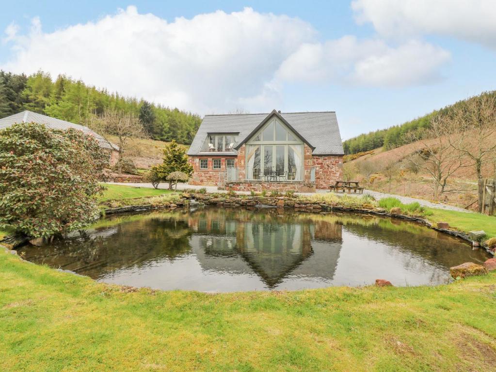 a house with a pond in front of it at Glen Cruick in Kirriemuir