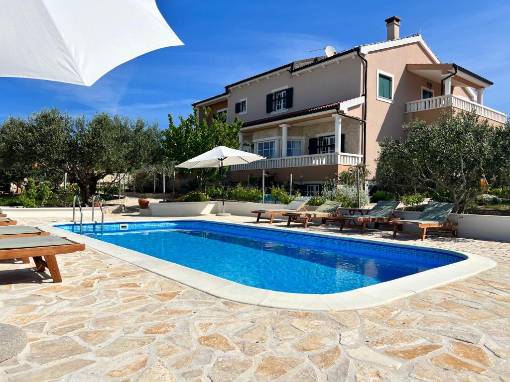 a swimming pool in front of a house at Apartments JoDi pool Novalja in Novalja