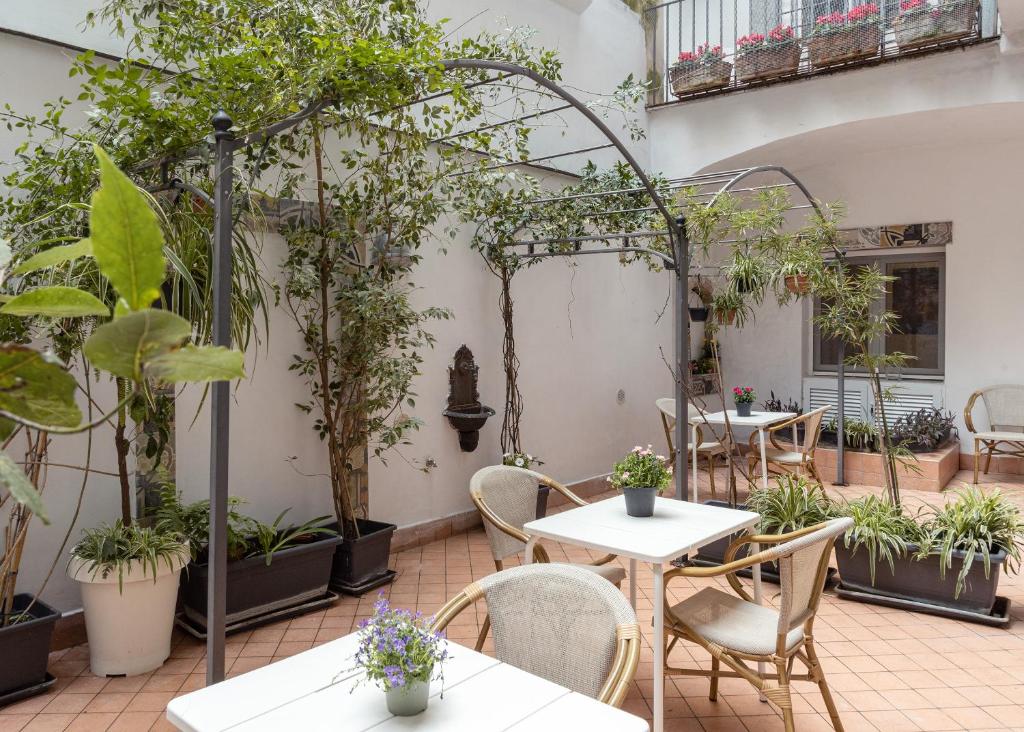 een patio met tafels, stoelen en planten bij Petrucci Garden by Enjoy Napoli in Napels