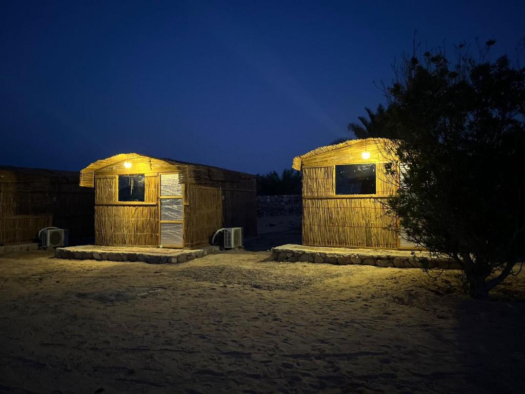 dos pequeñas estructuras de madera con luces encendidas por la noche en Mazih beach camp, en Nuweiba