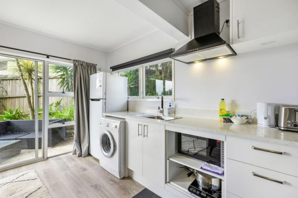 una cocina con lavadora y secadora. en A delight in the Bays - 1 BR - 1 BATH - Free WiFi, en Auckland