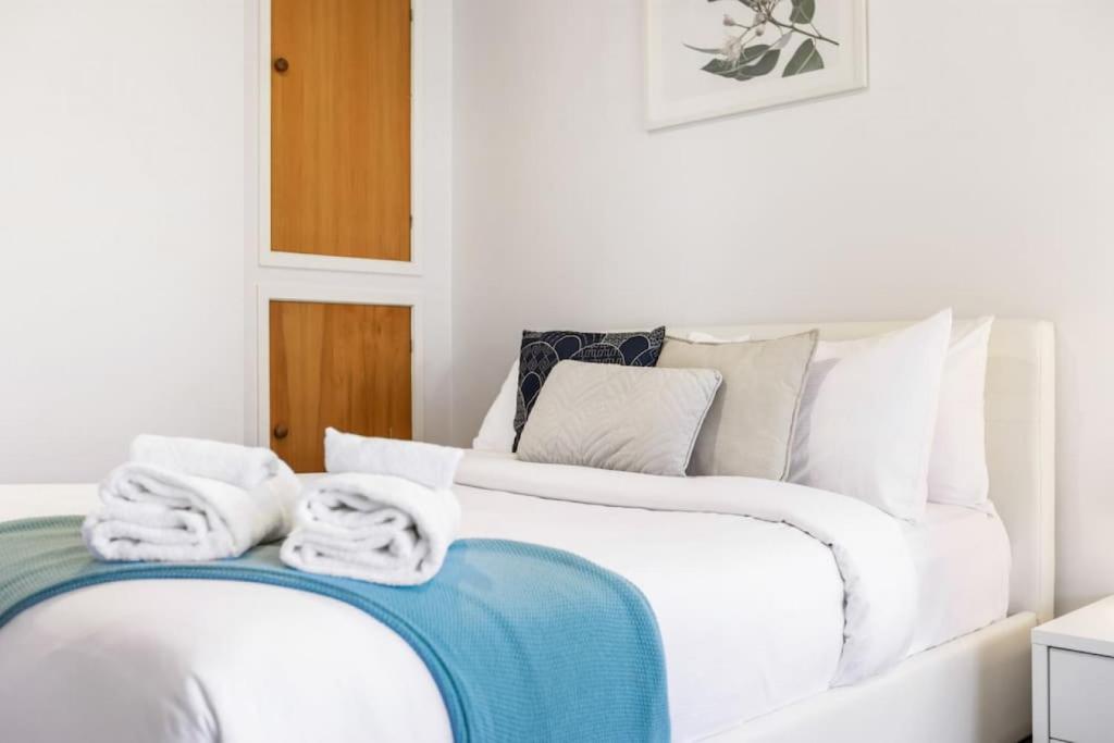 a white bed with towels on top of it at Torbay 1BR Bolthole - WiFi - Seaviews in Auckland