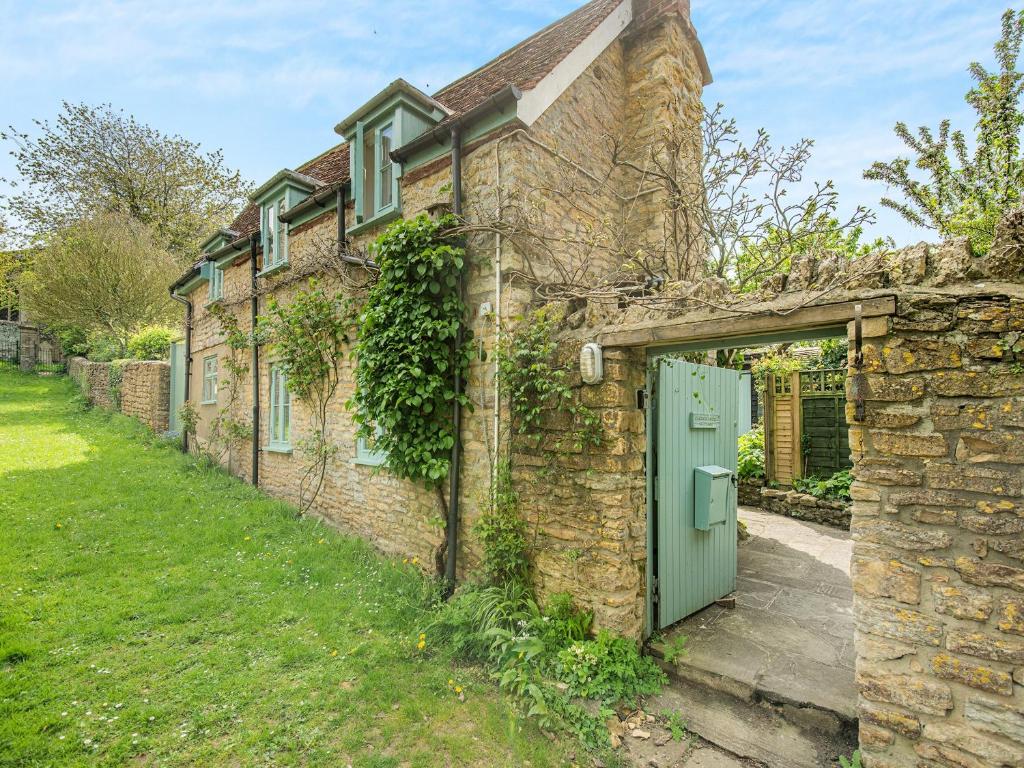a stone house with a green door in a yard at Church House Cottage in East Stour
